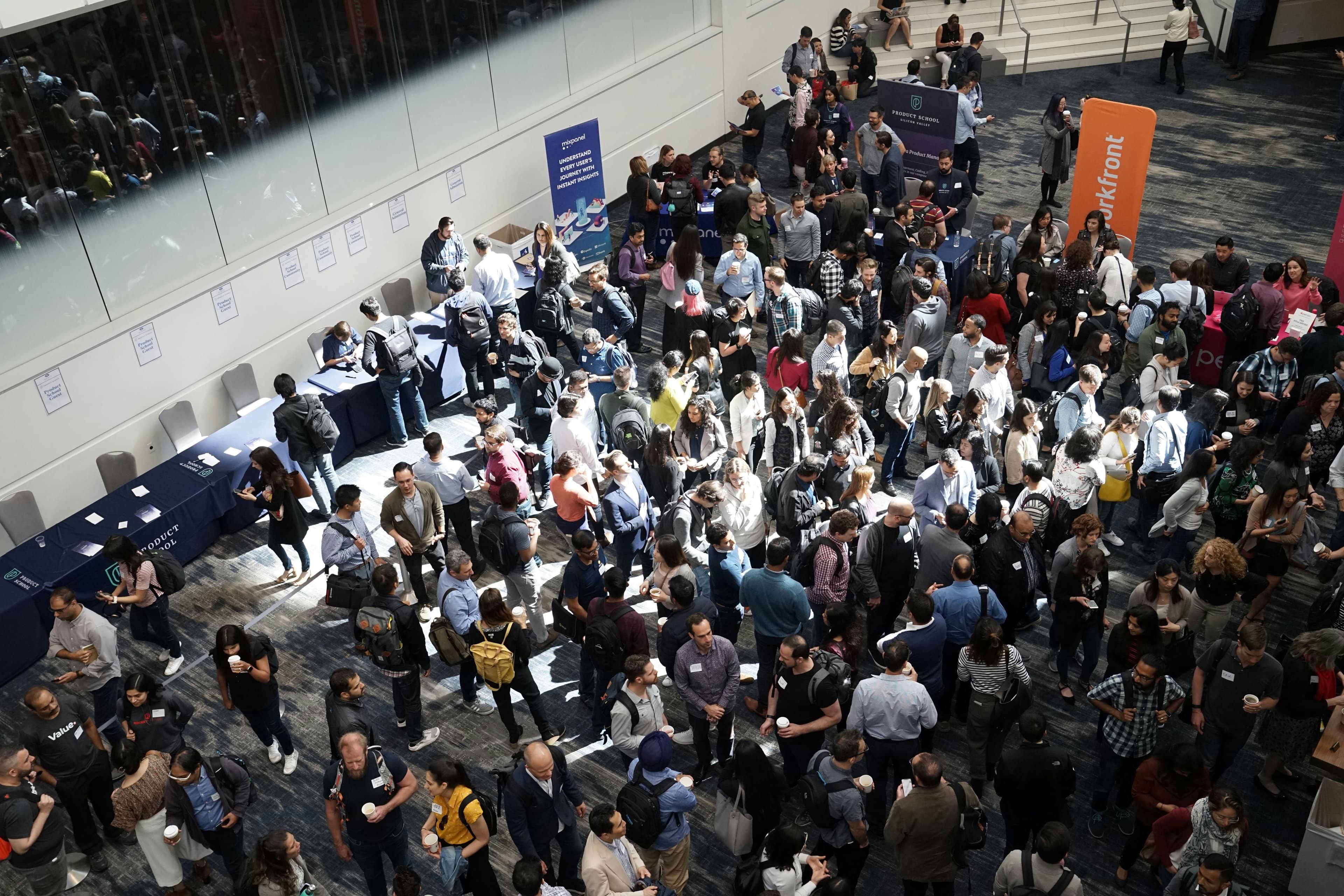 A crowded event floor with people moving between vendor areas.